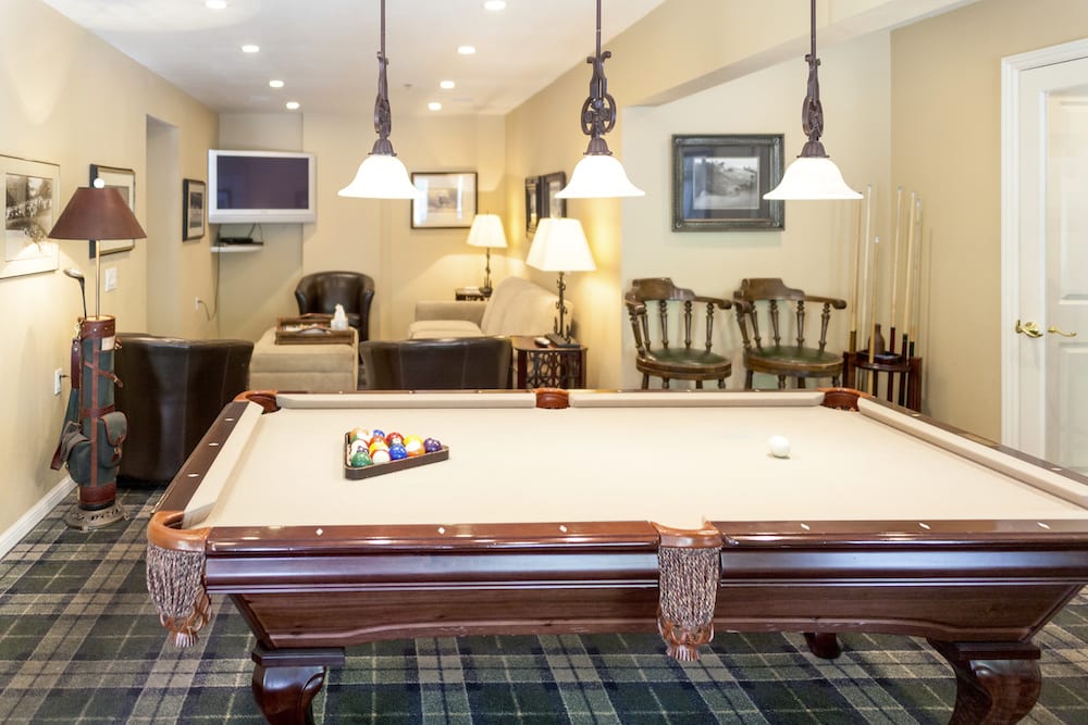 A cozy game room with a classic pool table and warm lighting.