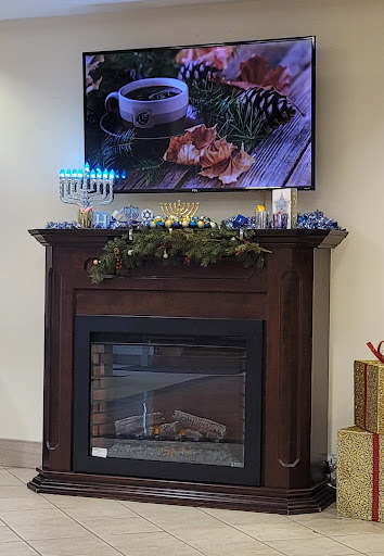 A cozy setting featuring a decorated fireplace with holiday decor and a TV displaying a warm beverage.