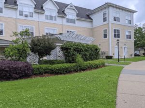 A view of a residential building with a well-maintained lawn and pathway.