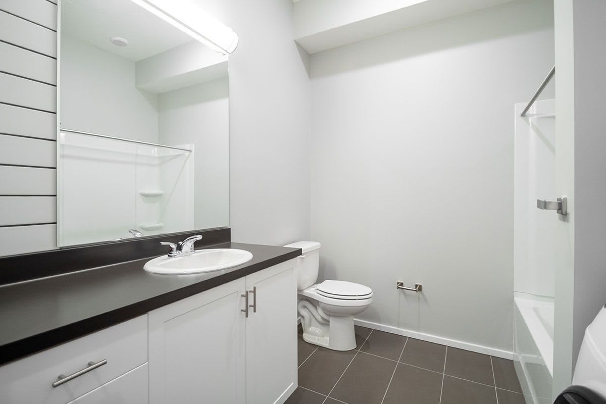 A modern, minimalist bathroom with a sink, mirror, and toilet.