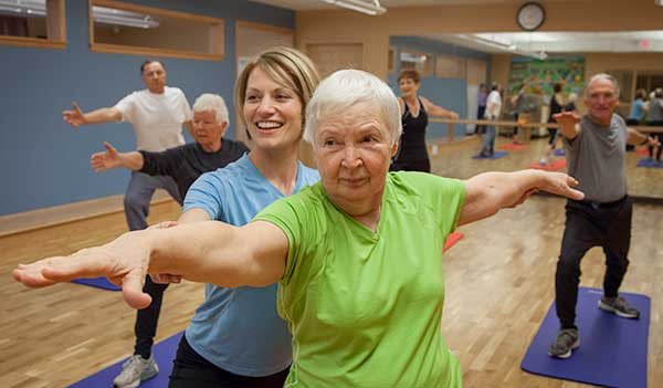 A group of elderly individuals participate in a yoga class, focusing on fitness and wellness.
