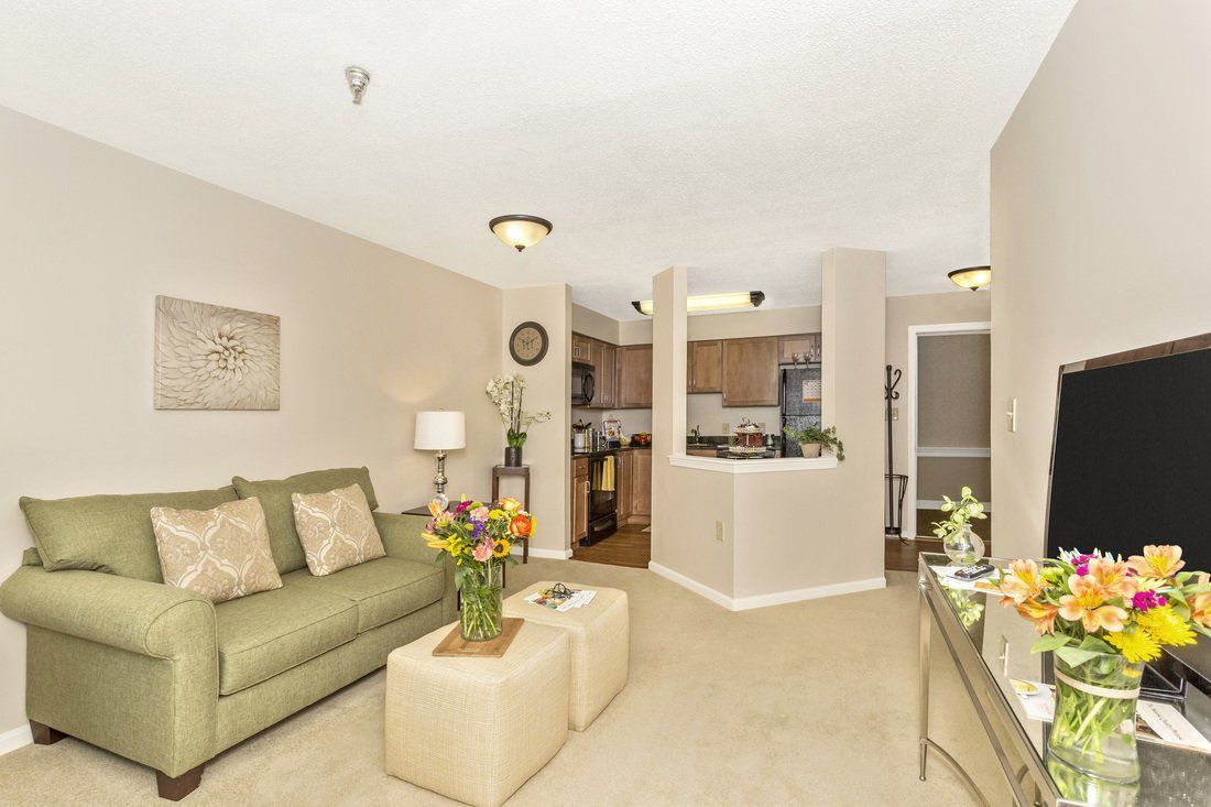 A cozy living room with a view into the kitchen, featuring modern furniture and elegant decor.