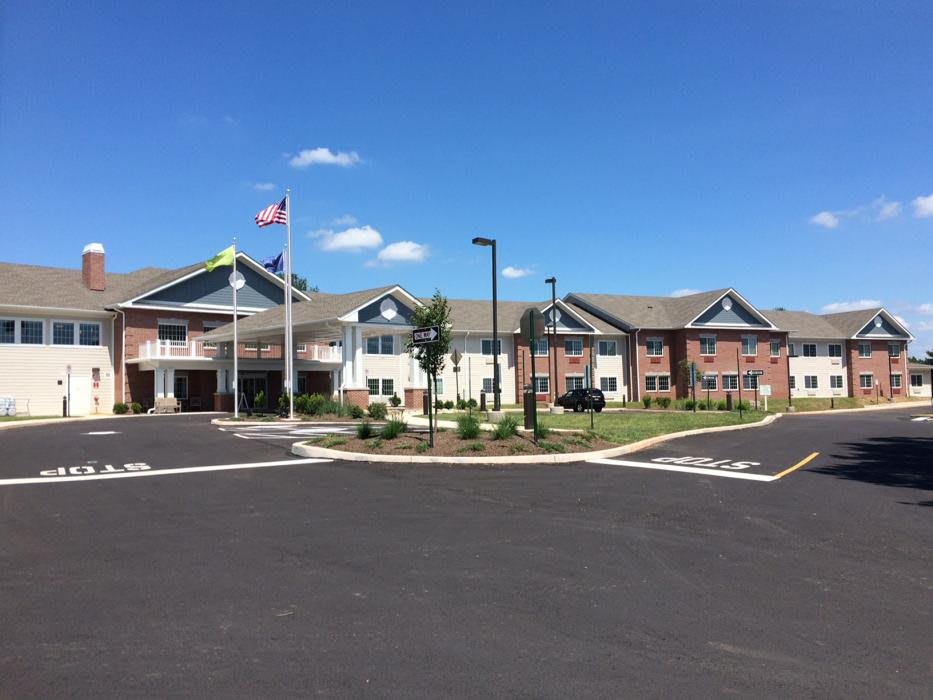 A large residential building with a well-maintained exterior, featuring flags and a clear blue sky.