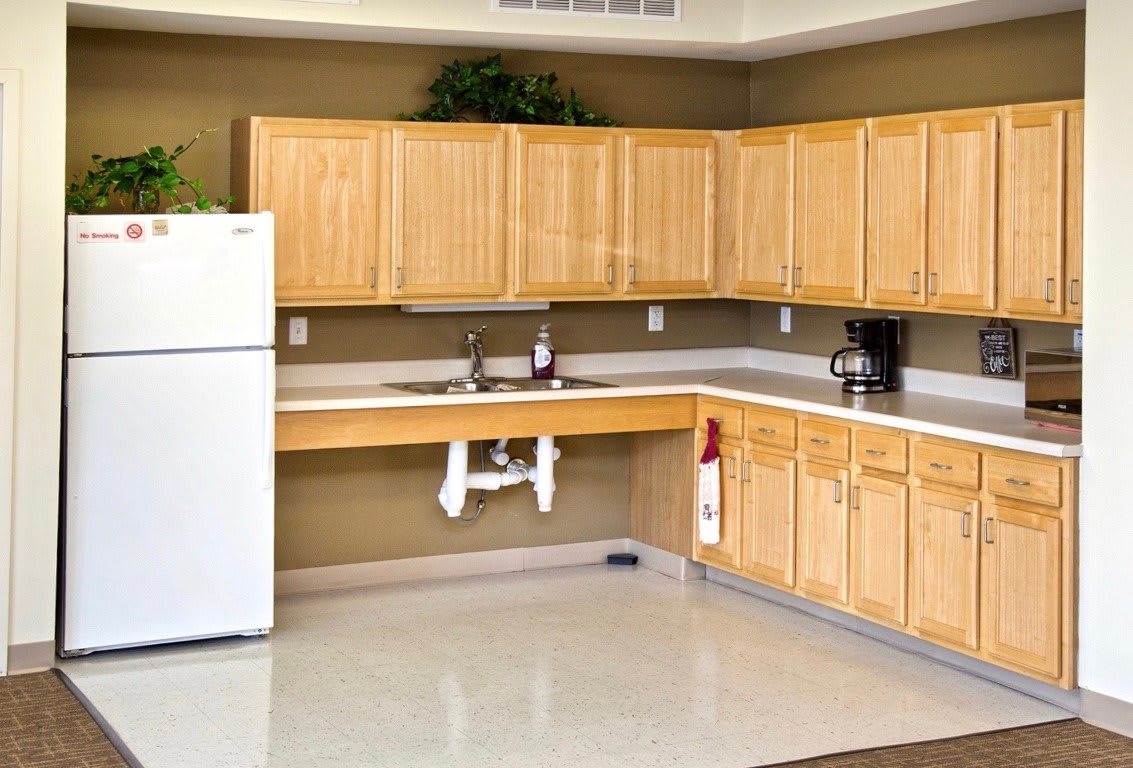 A spacious kitchen with wooden cabinets, a white refrigerator, and a modern countertop.