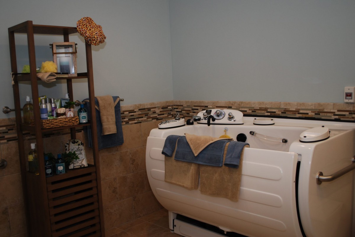 A cozy bathroom with a spa-like bathtub, neatly arranged towels, and a wooden shelf for storage.
