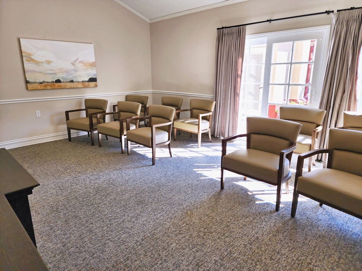 An empty waiting room with arranged chairs and natural light coming through the windows.