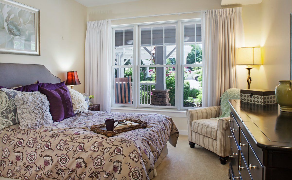 A cozy bedroom with elegant decor, featuring a large window overlooking a garden.