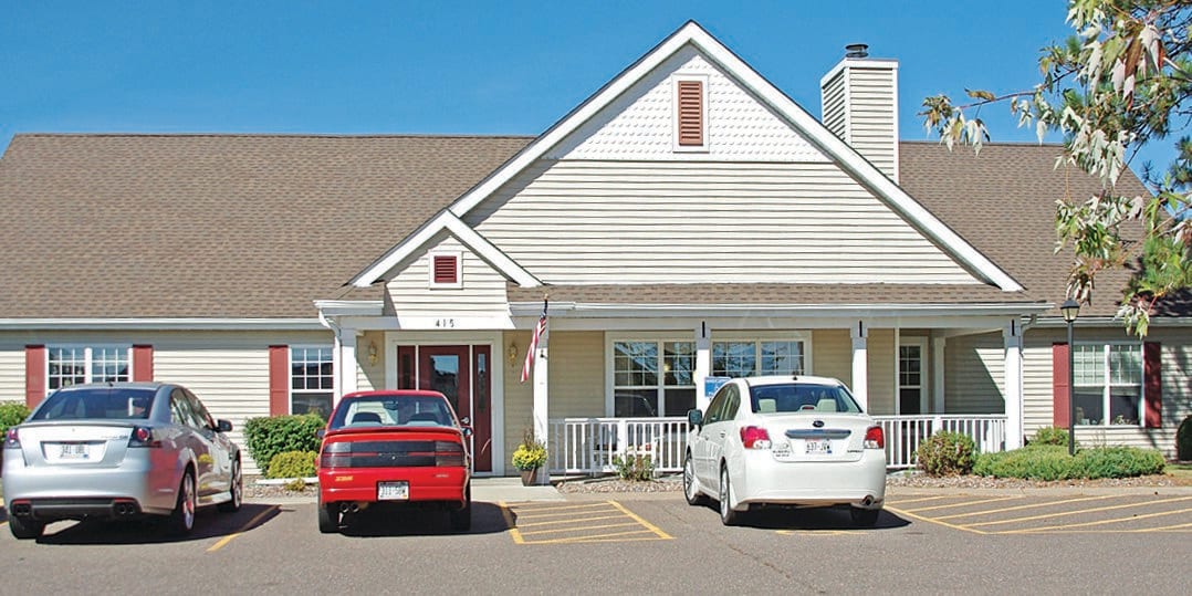 A suburban house with two cars parked in the driveway.