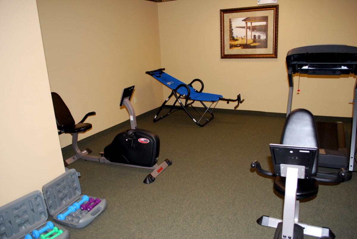 A small indoor fitness room with exercise equipment and wall art.