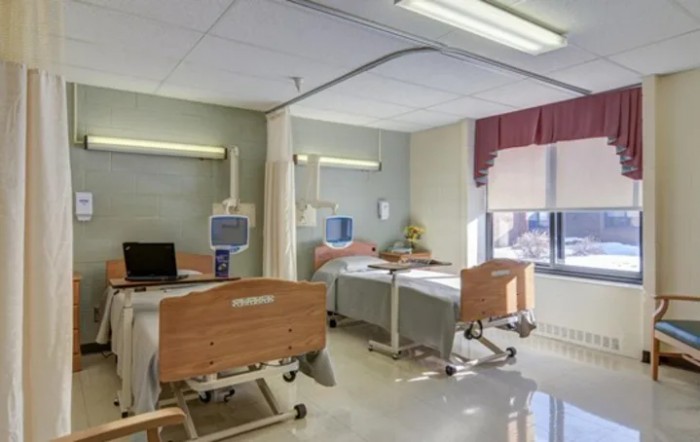 An empty hospital room with two patient beds and medical equipment.