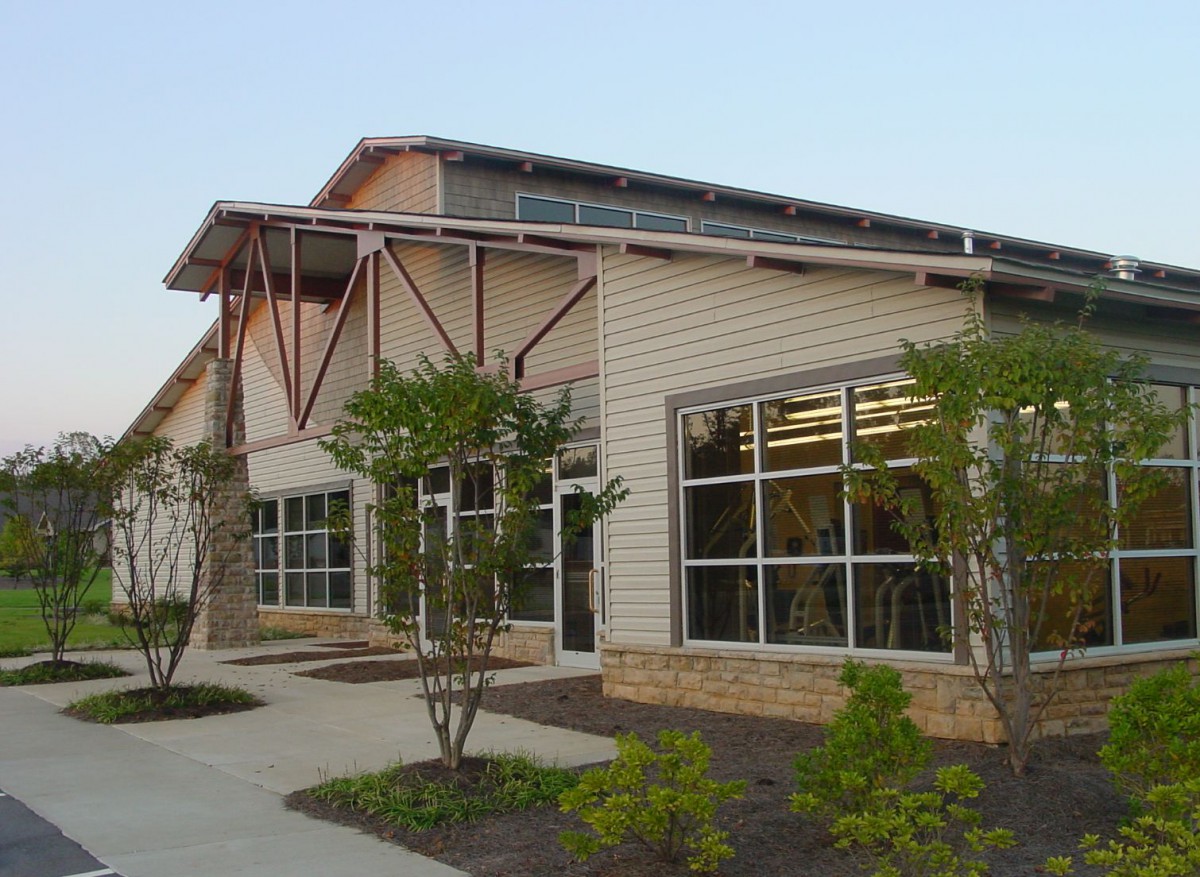 A modern library building with large windows surrounded by greenery.