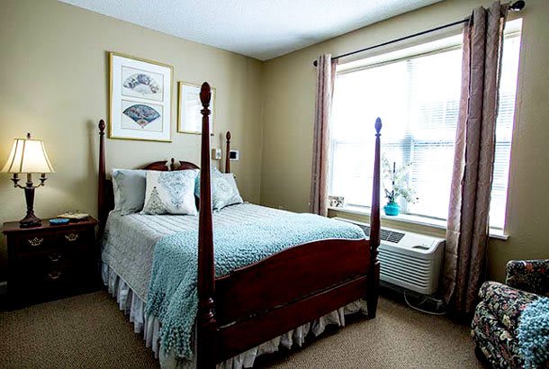 A traditional bedroom with a four-poster bed and large window.