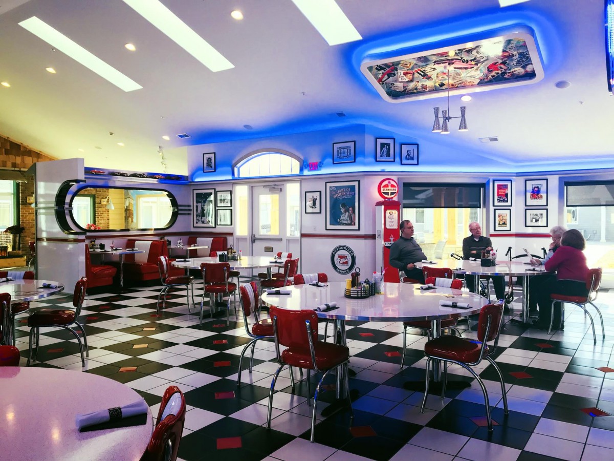 A retro-style diner with checkered flooring and neon lighting.