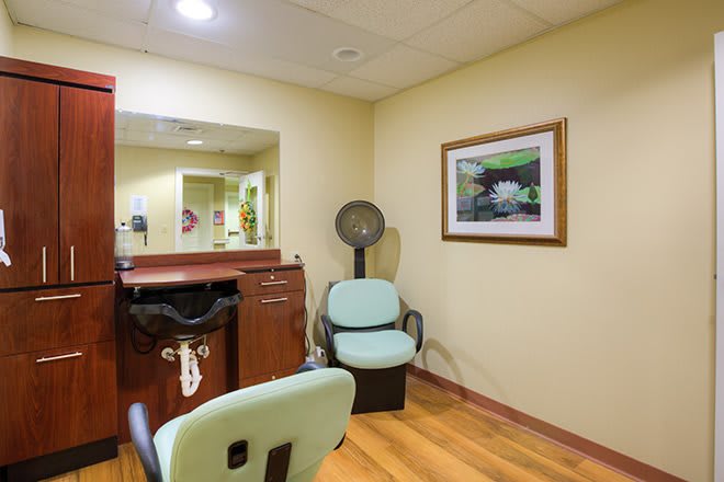A cozy hair salon interior with chairs, a mirror, and a vintage hair dryer.