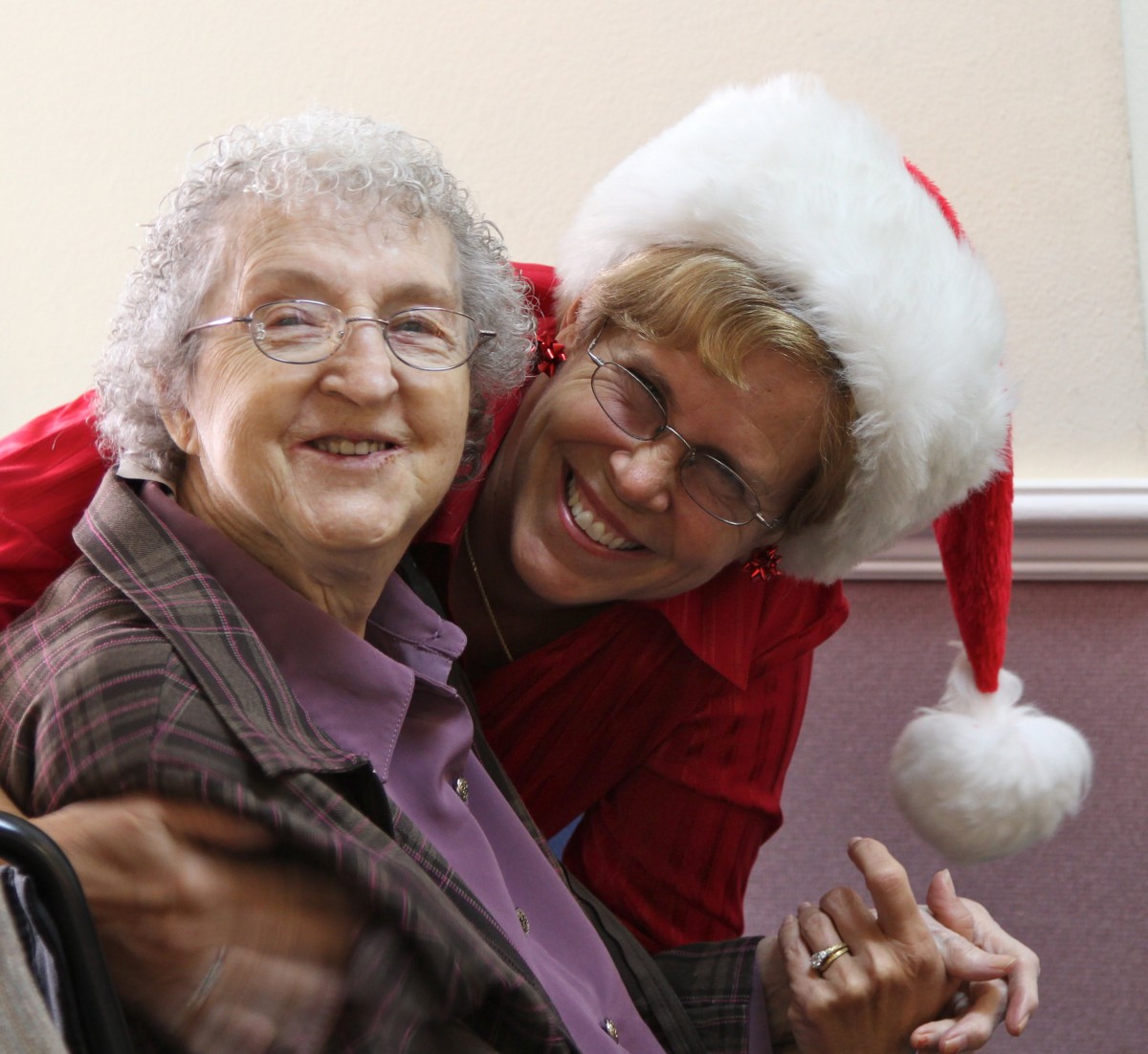Two people smiling together, one wearing a Christmas hat, enjoying a festive moment.