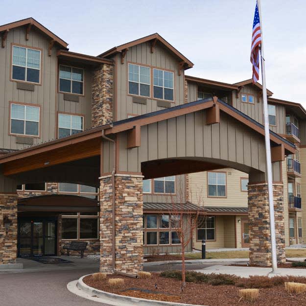 A hotel entrance with a stone facade and an American flag.