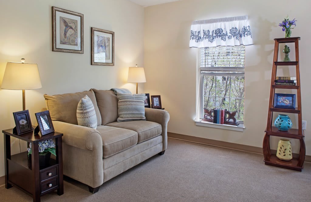 A cozy living room with a comfortable sofa, lamp, and decorative elements by the window.