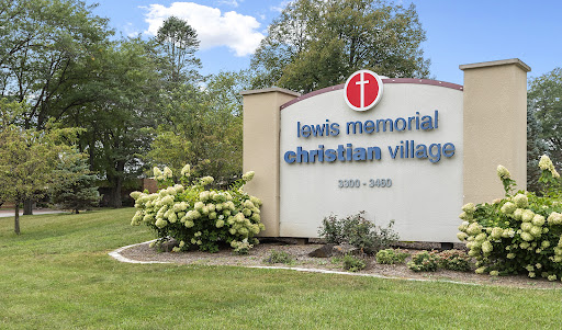 Entrance sign of Lewis Memorial Christian Village surrounded by lush greenery.