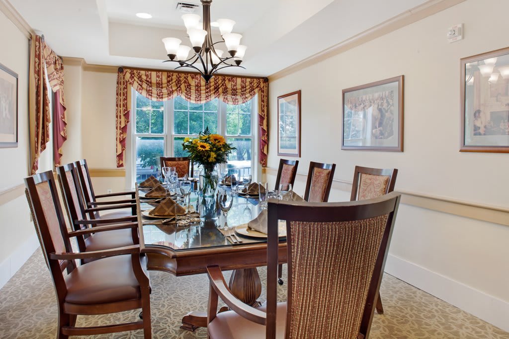 A well-decorated dining room with a set dining table, surrounded by elegant chairs and illuminated by a chandelier.