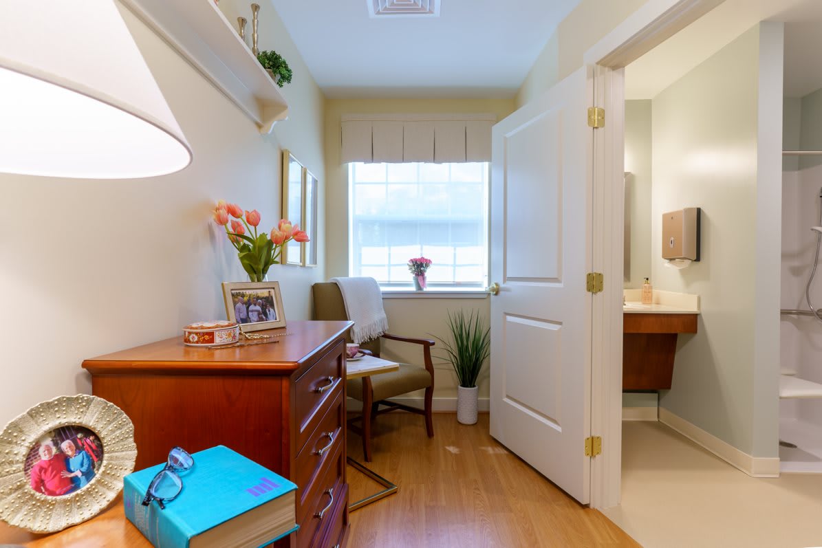 A cozy and bright bedroom with a desk and chair, featuring plants and decorative items.