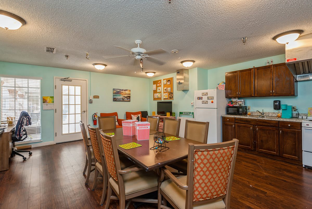 A cozy dining area adjoining a kitchen with a wooden table and chairs, decorated in warm tones.