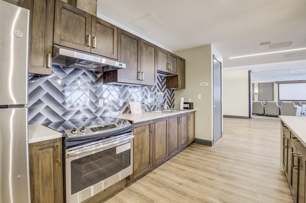 A modern kitchen featuring wooden cabinets, a stylish backsplash, and stainless steel appliances.