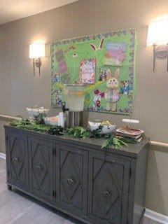 A festive Easter-themed refreshment station with a decorated bulletin board and lemonade dispenser.
