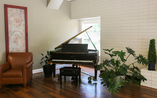 A grand piano elegantly placed in a bright, plant-adorned living room.