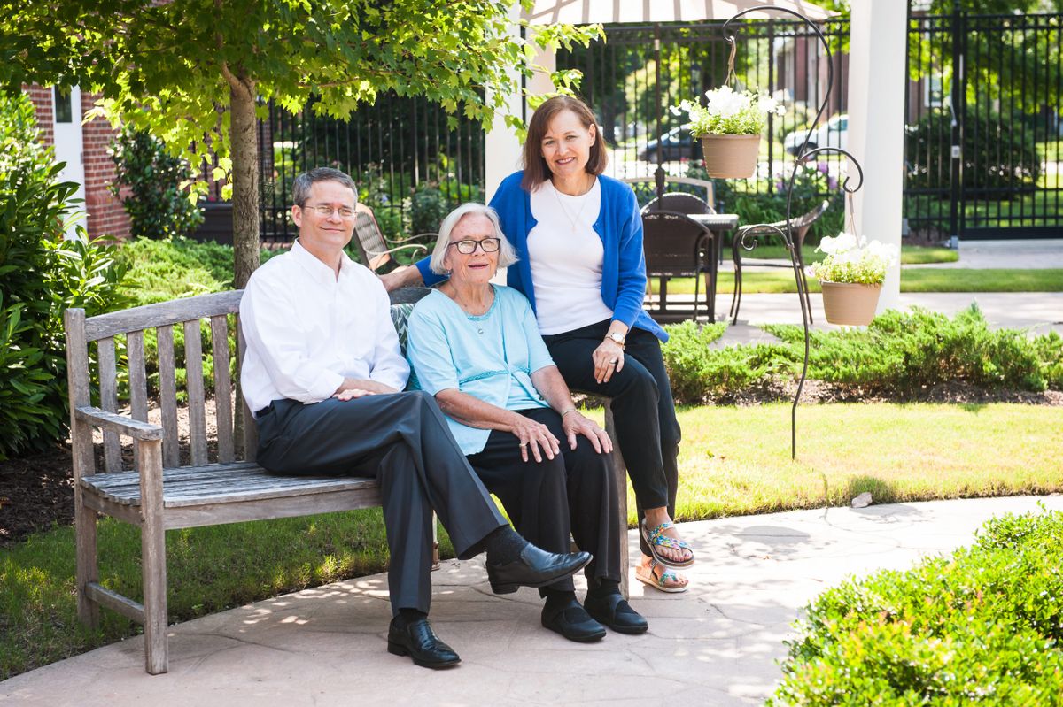 A family sitting on a bench in a garden, enjoying the outdoors together.