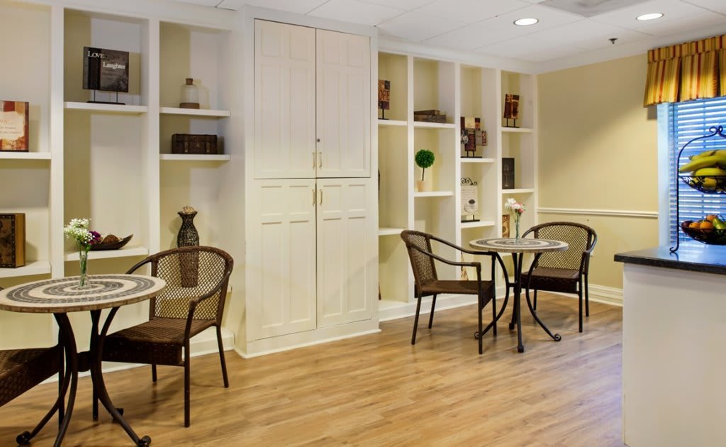 A cozy interior space featuring tables, chairs, and built-in shelves with decorative items.