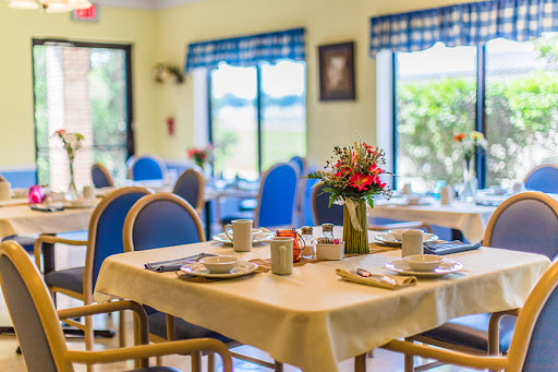 A cozy dining area set up for a meal, featuring tables adorned with dishes and a flower centerpiece.