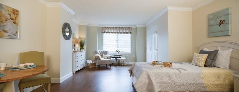A modern and spacious bedroom with natural lighting, featuring elegant decor and wooden flooring.