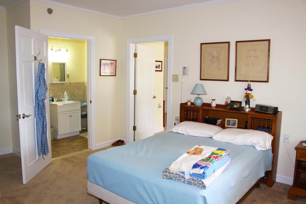 A cozy bedroom with a neatly made bed and an adjoining bathroom.