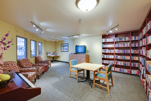 A cozy lounge area featuring comfortable seating, a television, and shelves filled with books.
