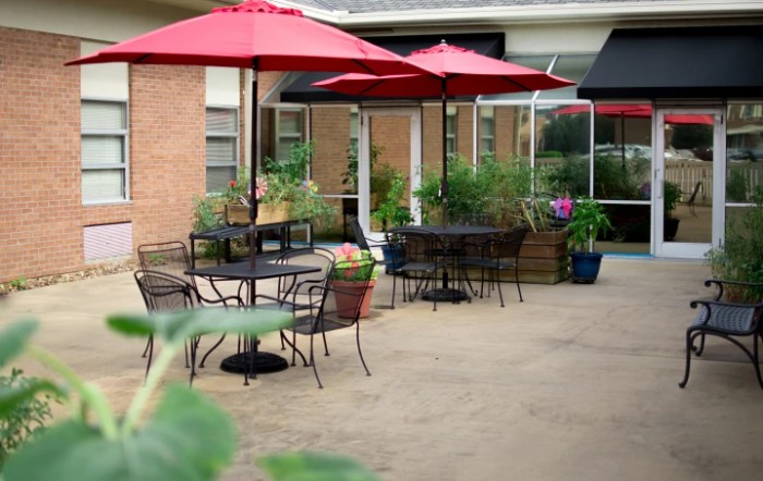 Charming outdoor patio area with red umbrellas and lush greenery.
