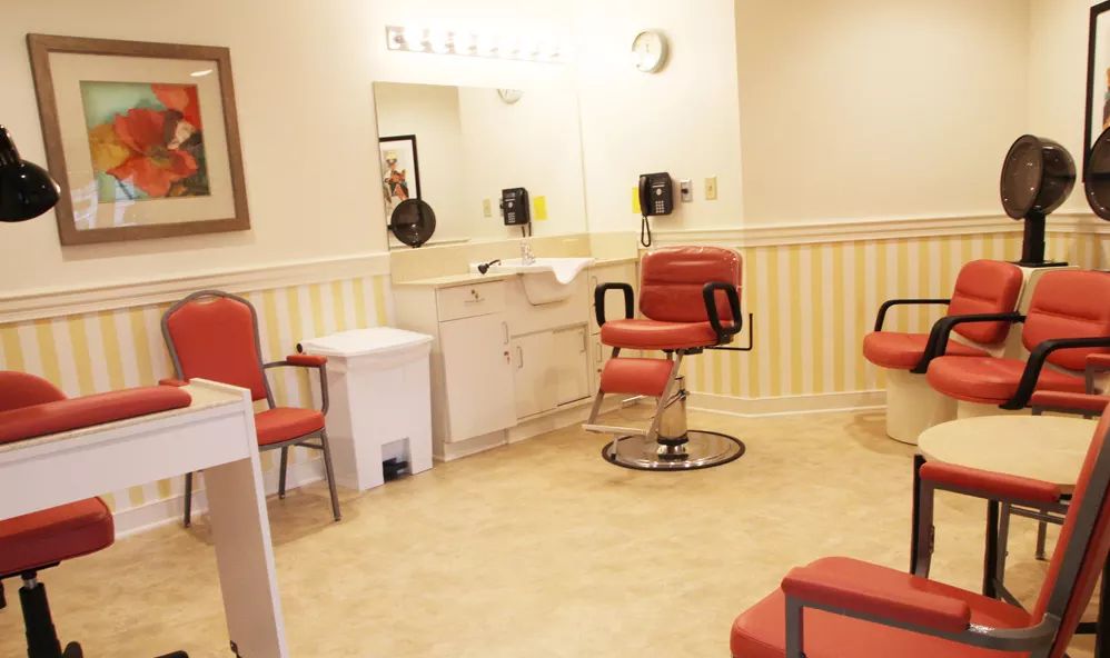 A well-lit salon interior featuring red hairdressing chairs and mirrors.