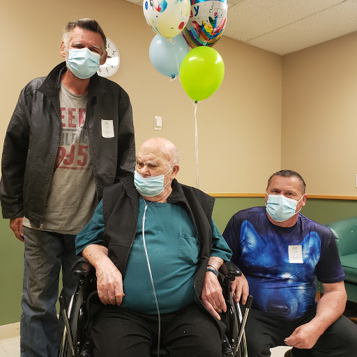 A family gathering in a healthcare setting, celebrating together with balloons.