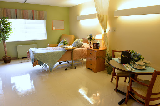 A well-lit hospital room featuring a patient bed, bedside table, and seating area.