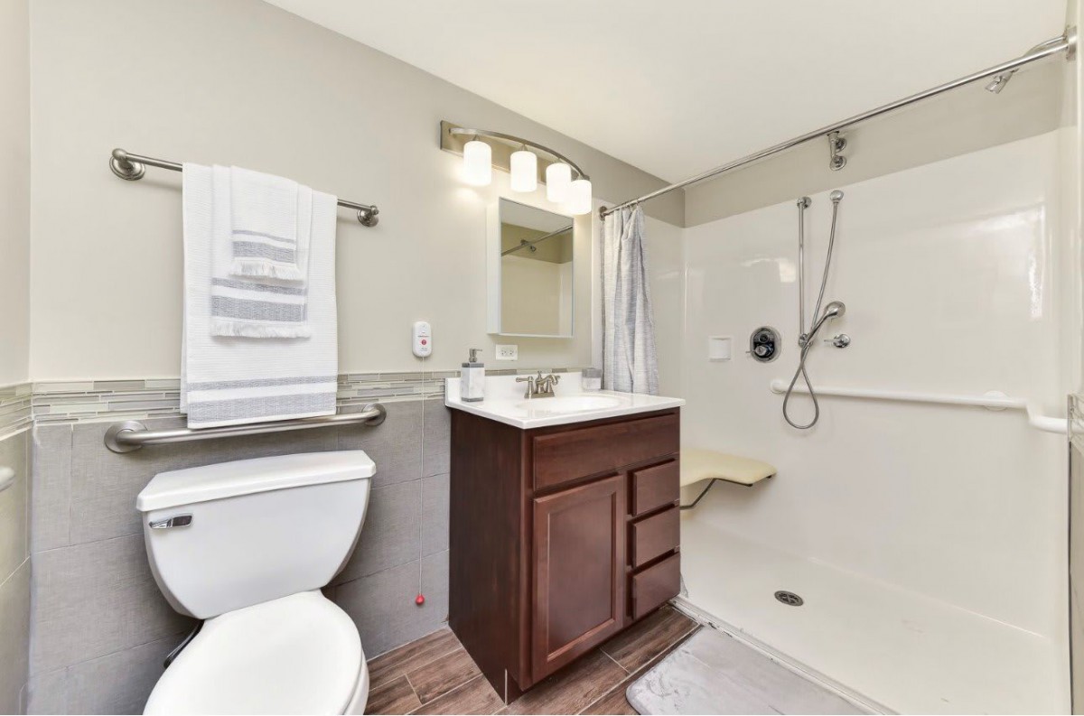 A modern bathroom with a shower, sink, and toilet.