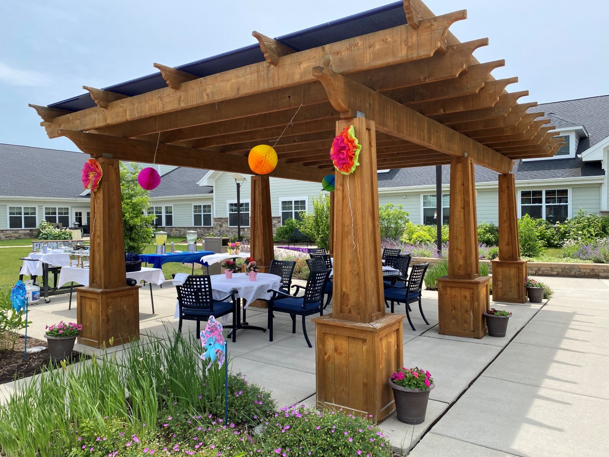 An outdoor pergola with tables and chairs, decorated with colorful lanterns.