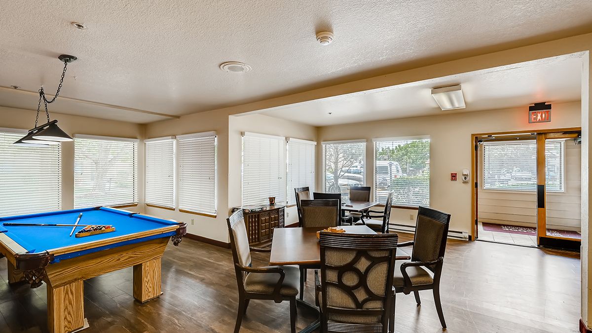 A game room featuring a pool table and seating area with tables and chairs.