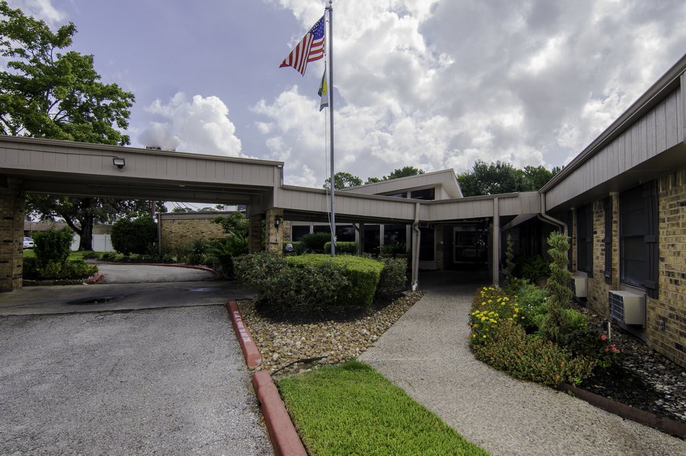 A building entrance with a flagpole and landscaped garden.