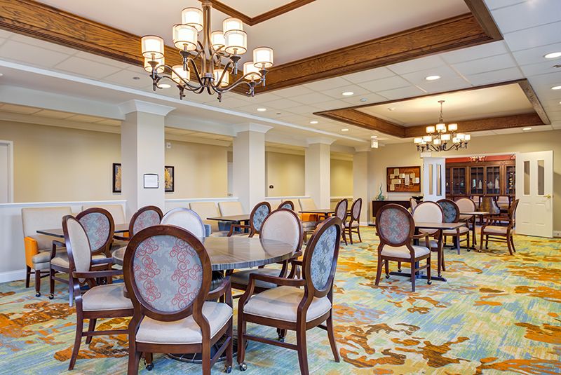 A spacious dining room with elegant chandeliers and classic furniture.
