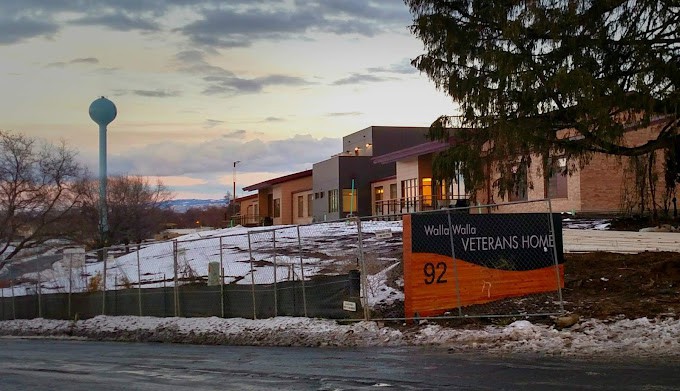 A building with a sign for a veterans home during sunset in winter, surrounded by snow.