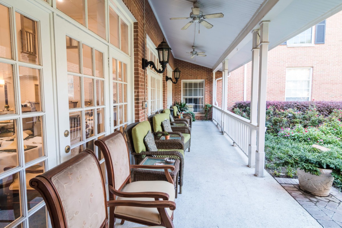 A cozy porch with cushioned chairs and ceiling fans, perfect for relaxation.