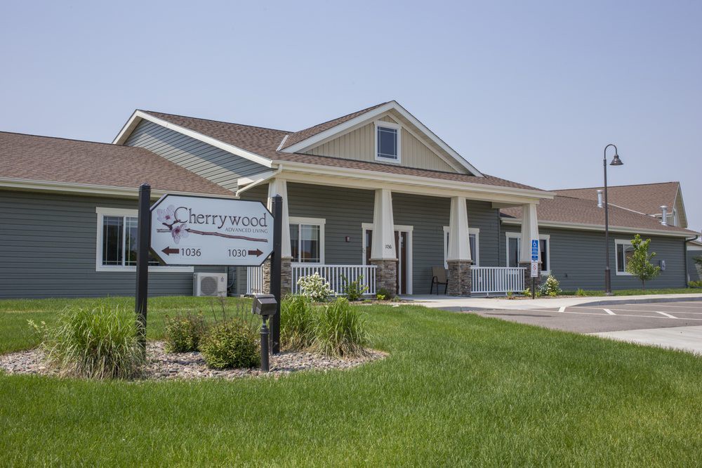 A residential building with a well-maintained lawn and a sign out front on a sunny day.