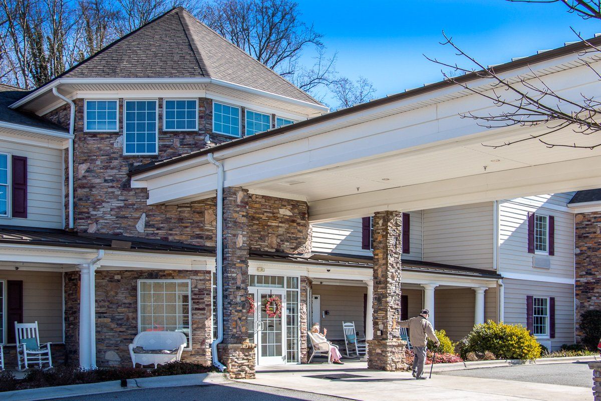 A residential building with a stone facade and covered entrance on a sunny day.