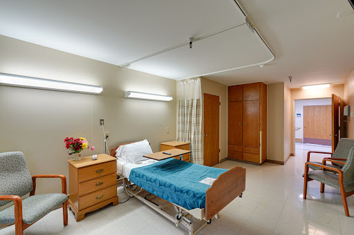 A well-organized hospital patient room featuring a bed, nightstand, and adequate lighting.