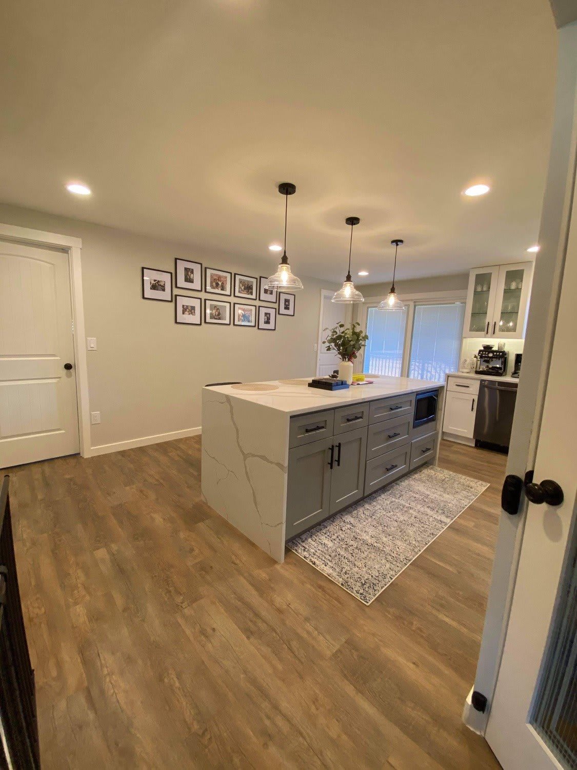 A modern kitchen interior featuring a central island and pendant lighting.