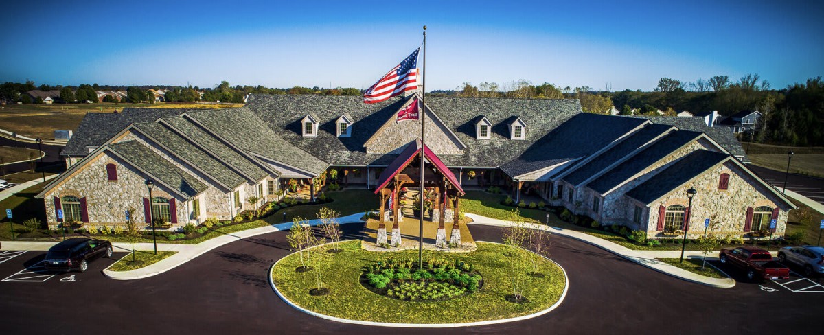 A large building with a circular driveway and an American flag in the foreground.